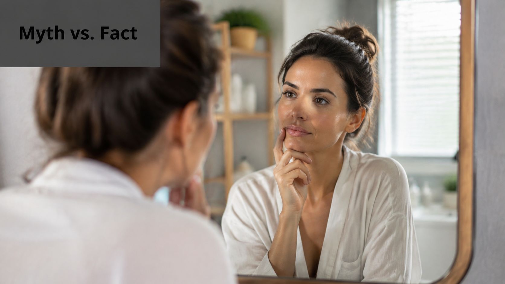 A woman looks at her reflection in a mirror while considering skincare myths versus facts.